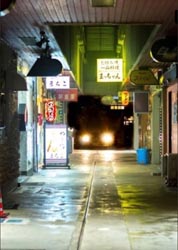 Photo of an alley with car headlights at the end